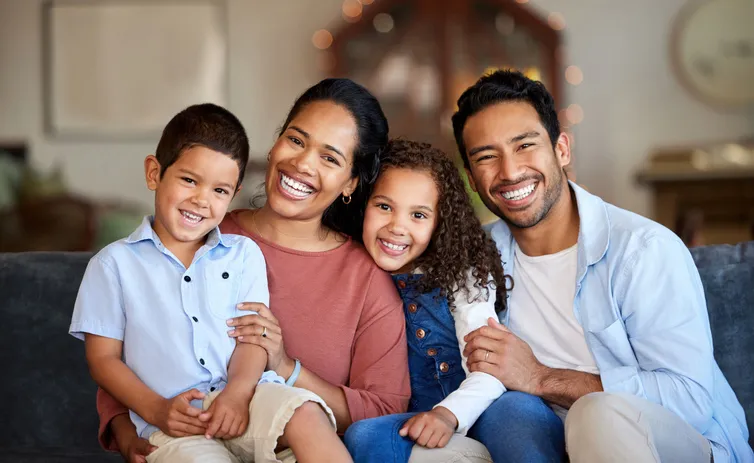 Portrait of smiling mixed race family relaxing together on sofa at home. Carefree loving hispanic parents bonding with cute little son and daughter. Happy kids spending quality time with mom and dad Portrait of smiling mixed race family relaxing together on sofa at home. Carefree loving hispanic parents bonding with cute little son and daughter. Happy kids spending quality time with mom and dad